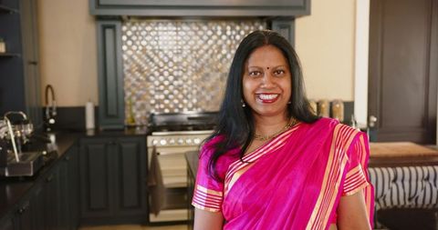 Smiling Indian Woman in Bright Sari Standing in Modern Kitchen