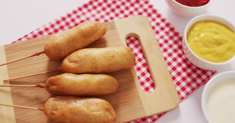 Corn Dogs and Condiments on Rustic Cutting Board