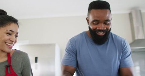 Friends smiling and cooking together in kitchen