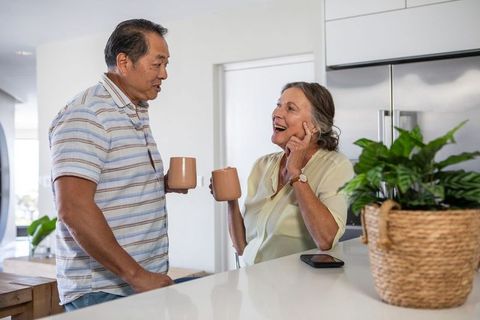 Diverse Senior Couple Enjoying Conversation Over Coffee in Modern Kitchen