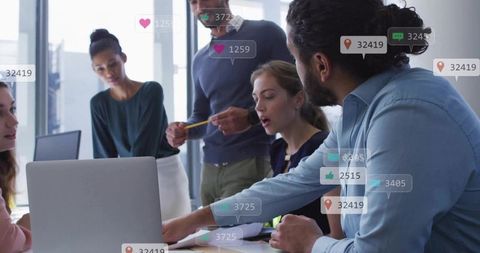 Collaborating team analyzing social metrics on laptop during office brainstorming session