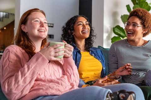 Smiling Friends Relaxing at Home with Snacks and Tea