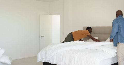 Father and Son Making Bed in Bright Minimalist Bedroom