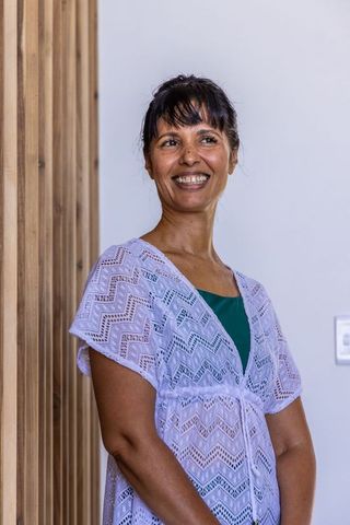 African american woman smiling in lavender lace coverup standing by wooden paneling