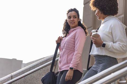 African american women walking up urban stairs carrying gym bags in hoodies and leggings