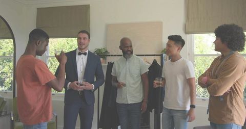 Man wearing tuxedo chatting with friends during casual living room wardrobe fitting