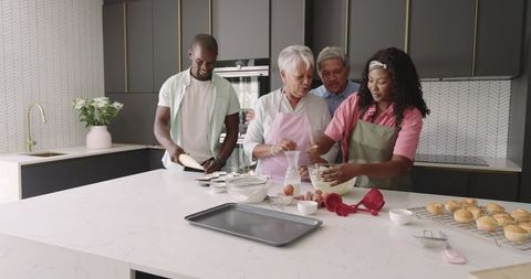 Multigenerational family baking together in modern kitchen mixing batter and muffins