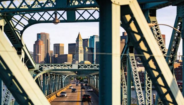 Sunlit steel truss bridge framing urban skyline guiding traffic over riverfront