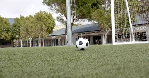 Resting soccer ball sitting on artificial turf beside goalpost on university campus field