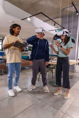Diverse coworkers testing VR headsets in modern office lounge collaborating on virtual project