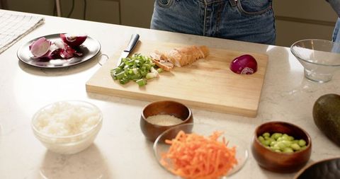 Multiethnic women chopping green onions on wooden cutting board for casual home meal prep