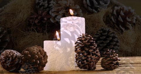 Cozy Holiday Ambiance with Lit Candles and Pine Cones