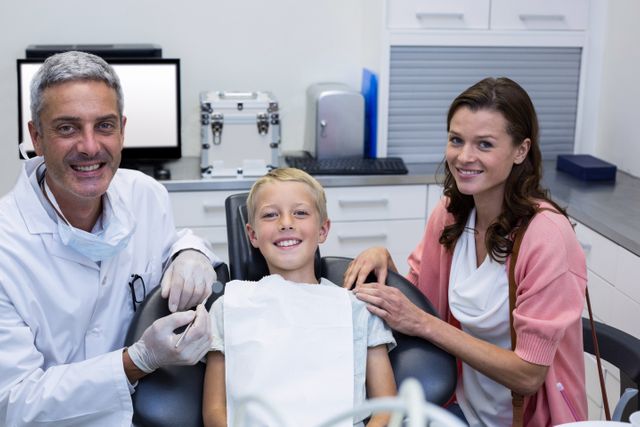 Dentist posing with young patient and his mother in a modern dental clinic. The dentist is smiling, and the child looks happy and comfortable. This image can be used for promoting dental services, pediatric dentistry, family healthcare, and oral hygiene education.