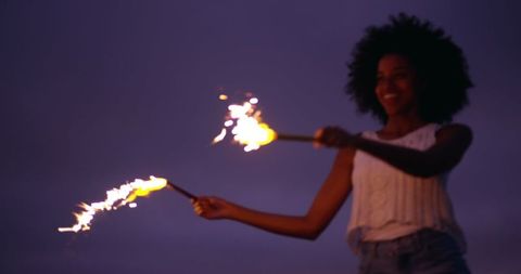 Young African American Woman Joyously Running with Sparklers at Dusk