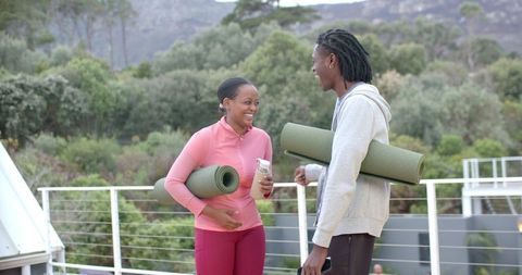 African American Friends Carrying Yoga Mats Laughing on Rooftop Deck After Outdoor Workout