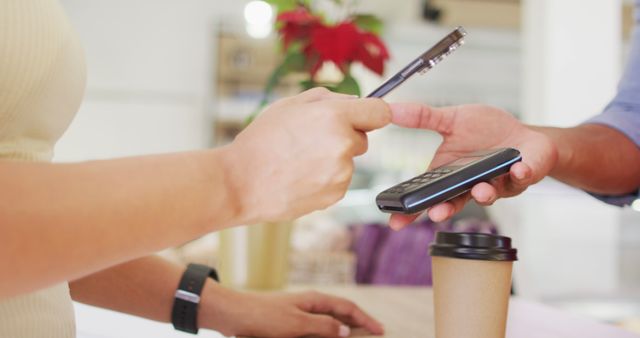 Image of hands of biracial woman paying with smartwatch for coffee. coffee and bistro shop, running small independent business.
