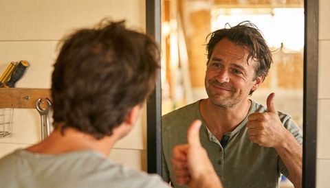 Handyman giving thumbs up in mirror during bathroom renovation showing diy confidence