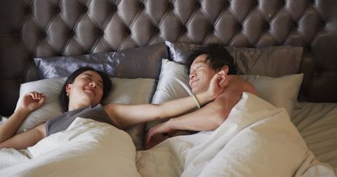 Romantic morning touch in luxurious bedroom with tufted headboard and cozy duvet