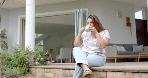 Relaxed Woman Enjoying Coffee Outdoors on Home Patio