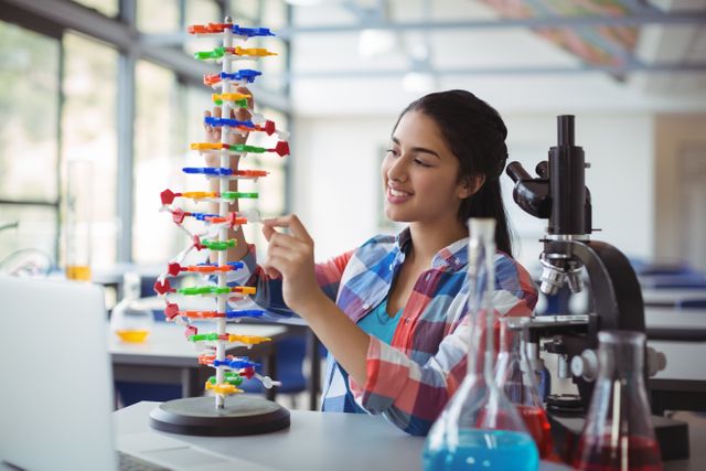 Attentive schoolgirl experimenting molecule model in laboratory at school