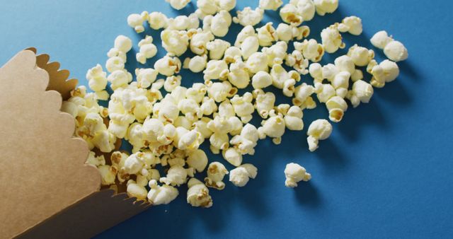 Popcorn Spilling from Box on Vivid Blue Background - Download Free Stock Images Pikwizard.com