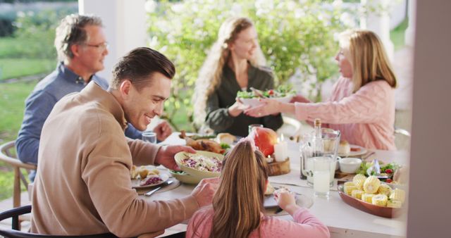 Image of happy caucasian parents, daughter and grandparents serving food at outdoor table. Family, domestic life and togetherness concept digitally generated image.