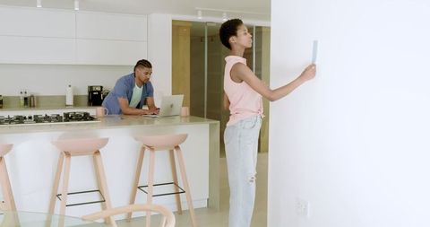 Couple Choosing Paint Colors in Modern Kitchen Dialing Laptop