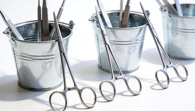 Displaying sterile surgical forceps and tweezers in galvanized buckets on white tabletop