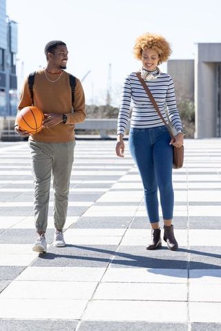 African american friends walking with basketball on urban plaza, sunny casual lifestyle