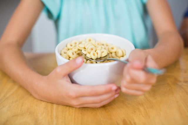Child enjoying a healthy breakfast cereal at home. Ideal for use in articles about children's nutrition, healthy eating habits, morning routines, or family life. Suitable for educational materials, parenting blogs, and food-related advertisements.