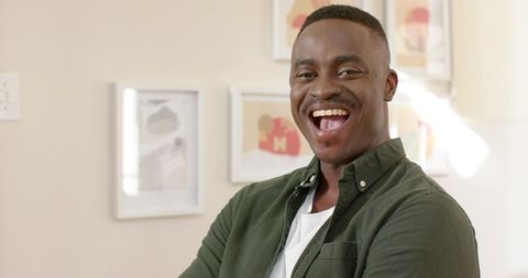 Laughing african american man crossing arms in bright casual home lifestyle portrait cozy
