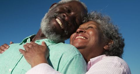 Happy Senior Couple Embracing on Beach Under Clear Sky