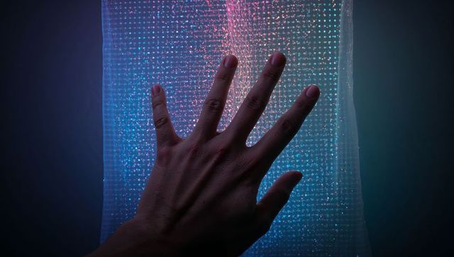 Pressing hand touching translucent micro-light panel with neon blue and pink glow