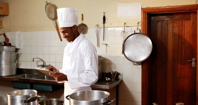 Chef in Commercial Kitchen Checking Tablet in Preparation for Cooking - Download Free Stock Images Pikwizard.com