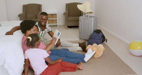 Happy Family Bonding While Reading Book on Bedroom Floor