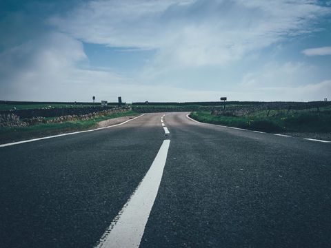 Plain open country road leading to horizon under clear sky