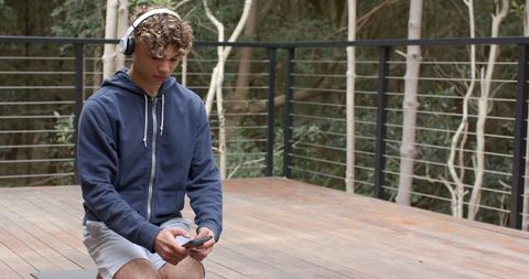 Young Man Relaxing Outdoors with Smartphone and Headphones