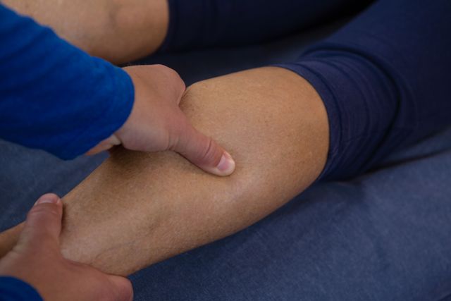 Physiotherapist giving leg massage to patient in clinic. Useful for articles on physical therapy, rehabilitation, healthcare services, and wellness treatments. Ideal for illustrating professional medical care and therapeutic practices.