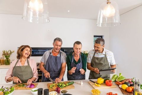 Senior friends cooking together sharing laughter in modern kitchen
