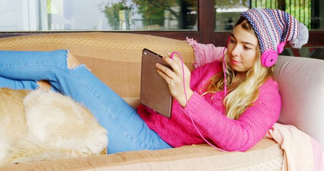 Young Woman Relaxing on Sofa with Tablet and Pink Headphones - Download Free Stock Images Pikwizard.com