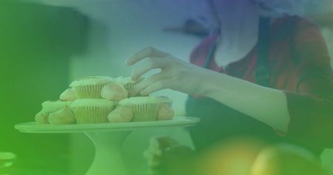 Woman arranging cupcakes on cake stand in kitchen