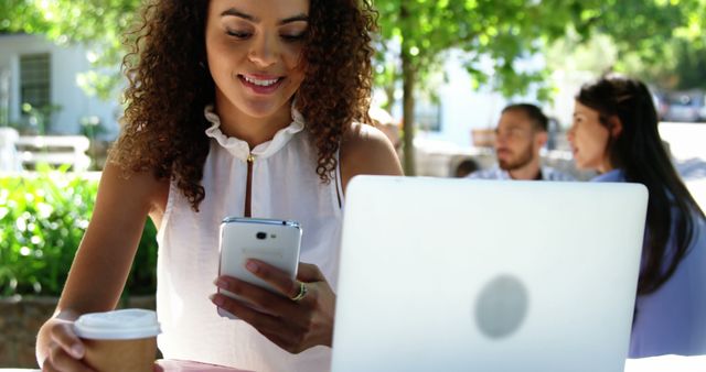 Smiling Woman Using Smartphone and Laptop in Outdoor Cafe - Download Free Stock Images Pikwizard.com