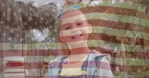 Smiling girl with american flag overlay in sunny garden
