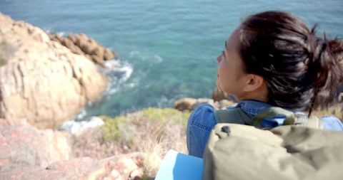 Woman Hiking with Backpack, Gazing at Ocean from Mountain Cliff