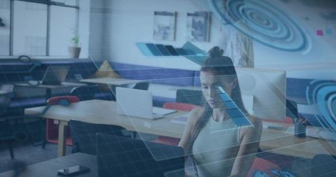 Young woman working on laptop in modern coworking space with holographic ui overlay