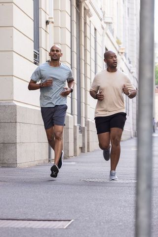 African american men running together on urban sidewalk for morning fitness and wellbeing