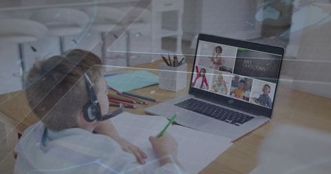 Young Student Attending Virtual Classroom Wearing Headset Writing Notes at Home Desk