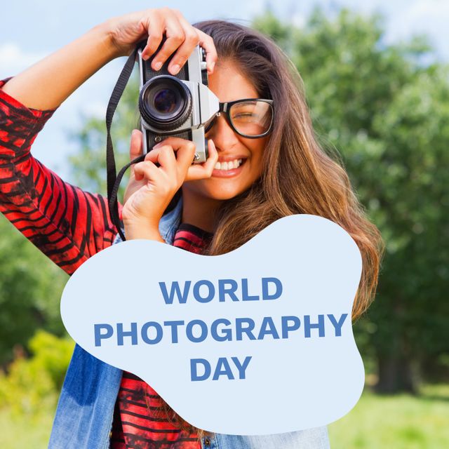 World photography day text on blue over happy biracial woman using camera in park. Global celebration of photography campaign, digitally generated image.
