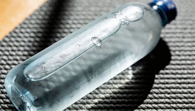 Condensation on Clear Plastic Water Bottle Lying on Textured Exercise Mat with Blue Cap