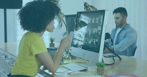 Woman Pointing at Video Conference on Monitor in Open Office While Colleague Filming